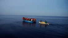 auf dem Bild ist ein Boot mit vielen Menschen zu sehen. Geflüchtete auf dem Mittelmeer. Ein zweites kleines Boot steuert auf sie zu.