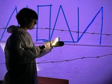 Frau mit Taschenlampe hinter Stacheldraht