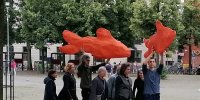 eine Gruppe von Menschen trägt zwei große orangene Fische