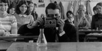 Ein mann, der durch eine Kamera schaut. Das bild ist schwarz weiß, und stammt aus einer Aufnahme aus 1968